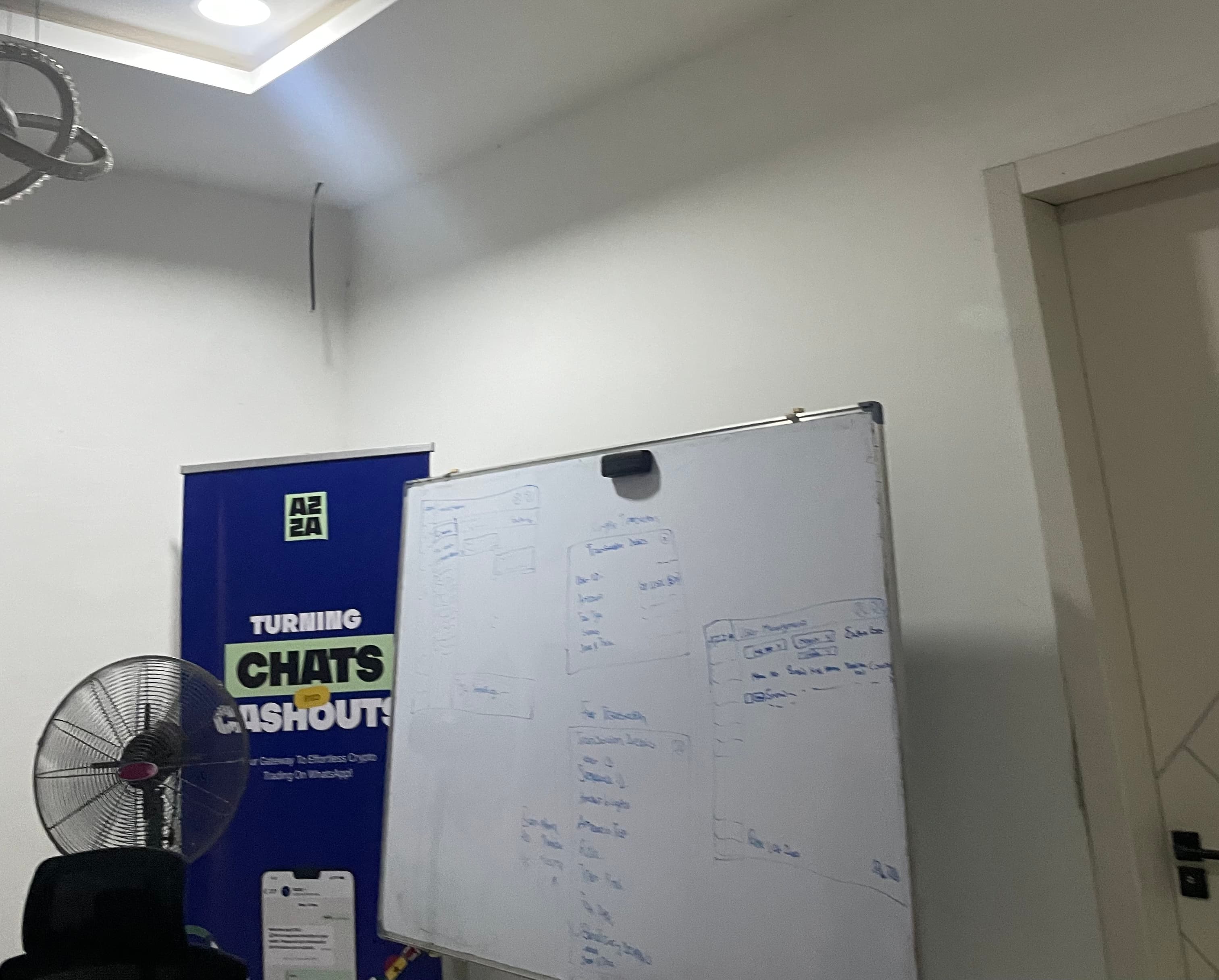 The Azza team gathered around a whiteboard sketching app flows during an ideation session